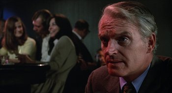 Movie still from “Joe” (1970), directed by John G. Avildsen – An older man in a suit and tie looking to his left; Close Up shot, Over the shoulder angle