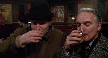 Movie still from “Joe” (1970), directed by John G. Avildsen – Two men are sitting at a bar and one is drinking a beverage; Close Up shot, Low angle