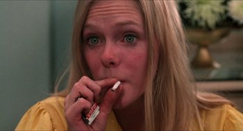 Movie still from “Joe” (1970), directed by John G. Avildsen – A woman is taking a bite out of a cigarette; Close Up shot, High angle