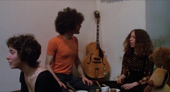 Movie still from “Joe” (1970), directed by John G. Avildsen – A group of people sitting at a table with a guitar; Medium shot, High angle