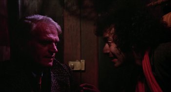 Movie still from “Joe” (1970), directed by John G. Avildsen – Two men are talking in a dark room; Close Up shot, Over the shoulder angle