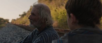 Movie still from “Joe” (2013), directed by David Gordon Green – A man with long hair and a gray beard is sitting next to another man; Close Up shot, Over the shoulder angle