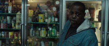 Movie still from “Joe” (2013), directed by David Gordon Green – A man standing in front of a display case filled with bottles; Close Up shot, Over the shoulder angle