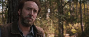Movie still from “Joe” (2013), directed by David Gordon Green – A person with a beard in the woods; Close Up shot, Over the shoulder angle