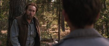 Movie still from “Joe” (2013), directed by David Gordon Green – A man standing next to a tree in the woods; Close Up shot, Over the shoulder angle