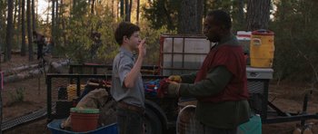 Movie still from “Joe” (2013), directed by David Gordon Green – A boy and a man are standing in front of a truck; Medium shot, Over the shoulder angle