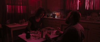 Movie still from “Joe” (2013), directed by David Gordon Green – Two people sitting at a table in a dark room; Medium shot, Over the shoulder angle