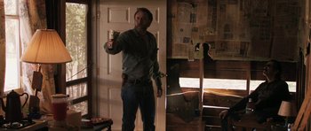 Movie still from “Joe” (2013), directed by David Gordon Green – A man standing in a room holding a beer; Medium shot, Low angle