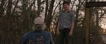 Movie still from “Joe” (2013), directed by David Gordon Green – A man standing next to an older woman in the woods; Medium shot, Over the shoulder angle