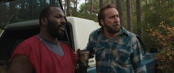 Movie still from “Joe” (2013), directed by David Gordon Green – A man holding a cup next to another man in plaid shirt; Close Up shot, Over the shoulder angle