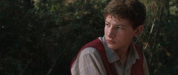 Movie still from “Joe” (2013), directed by David Gordon Green – A young man in a plaid shirt and a red vest; Close Up shot, Over the shoulder angle