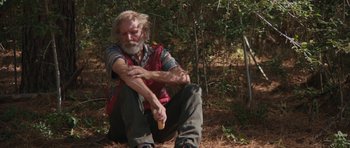 Movie still from “Joe” (2013), directed by David Gordon Green – An older man sitting on the ground in the woods; Medium shot, Over the shoulder angle