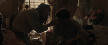 Movie still from “Joe” (2013), directed by David Gordon Green – A woman is putting lipstick on a young man; Medium shot, Over the shoulder angle