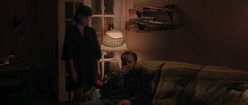 Movie still from “Joe” (2013), directed by David Gordon Green – A man sitting on a couch next to a woman; Medium shot, Over the shoulder angle