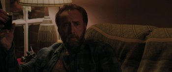 Movie still from “Joe” (2013), directed by David Gordon Green – A person sitting on a couch in a living room; Close Up shot, Over the shoulder angle