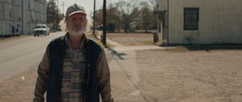 Movie still from “Joe” (2013), directed by David Gordon Green – An older man standing on the side of the street; Medium shot, Over the shoulder angle