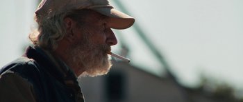 Movie still from “Joe” (2013), directed by David Gordon Green – An old man with a beard and a hat smoking a cigarette; Close Up shot, Over the shoulder angle