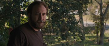 Movie still from “Joe” (2013), directed by David Gordon Green – A man with a goatee is standing in front of trees; Close Up shot, Over the shoulder angle