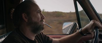 Movie still from “Joe” (2013), directed by David Gordon Green – A man with a cigarette in his mouth driving a car; Close Up shot, Over the shoulder angle