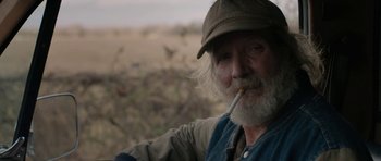 Movie still from “Joe” (2013), directed by David Gordon Green – An old man with a beard and a hat is smoking a cigarette; Close Up shot, Over the shoulder angle