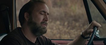 Movie still from “Joe” (2013), directed by David Gordon Green – A bearded man sitting in a car looking at his cell phone; Close Up shot, Low angle
