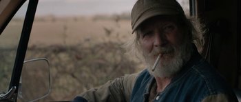 Movie still from “Joe” (2013), directed by David Gordon Green – An old man with a beard and a hat smoking a cigarette; Close Up shot, Over the shoulder angle