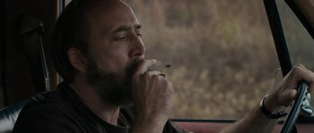 Movie still from “Joe” (2013), directed by David Gordon Green – A man smoking a cigarette while sitting in a car; Close Up shot, Over the shoulder angle