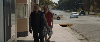 Two men walking down a sidewalk near a street