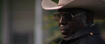 Movie still from “Joe” (2013), directed by David Gordon Green – A person wearing a hat and sunglasses; Close Up shot, Over the shoulder angle
