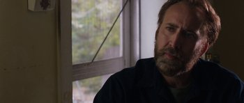 Movie still from “Joe” (2013), directed by David Gordon Green – A man with a goatee sitting in front of a window; Close Up shot, Over the shoulder angle