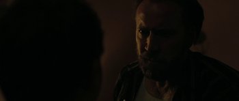 Movie still from “Joe” (2013), directed by David Gordon Green – A person with a beard looking at the camera; Close Up shot, Over the shoulder angle