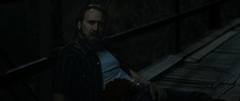 Movie still from “Joe” (2013), directed by David Gordon Green – A man with a beard is sitting in the dark; Medium shot, High angle