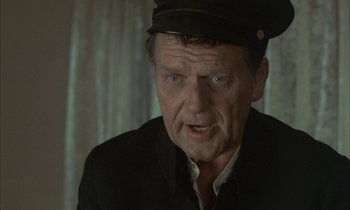 Movie still from “Johnny Got His Gun” (1971), directed by Dalton Trumbo – An older man wearing a black hat and a black jacket; Close Up shot, Over the shoulder angle