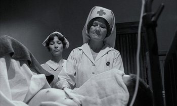 Movie still from “Johnny Got His Gun” (1971), directed by Dalton Trumbo – Two nurses are standing next to a baby in a hospital bed; Medium shot, Low angle