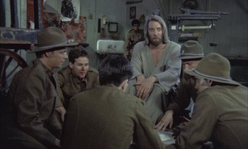 Movie still from “Johnny Got His Gun” (1971), directed by Dalton Trumbo – A group of men sitting in a room with a man in a robe; Medium shot, Over the shoulder angle