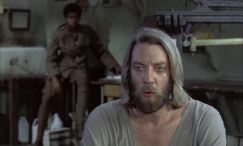 Movie still from “Johnny Got His Gun” (1971), directed by Dalton Trumbo – A man with long hair and a long beard; Medium shot, Over the shoulder angle