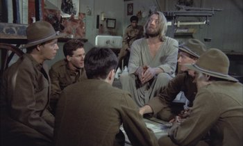 Movie still from “Johnny Got His Gun” (1971), directed by Dalton Trumbo – A group of men sitting in a room with a man in a robe; Medium shot, High angle