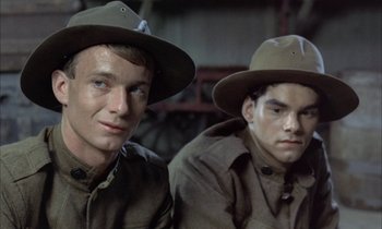 Movie still from “Johnny Got His Gun” (1971), directed by Dalton Trumbo – Two young men wearing hats are posing for a picture; Close Up shot, Over the shoulder angle