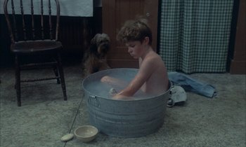 Movie still from “Johnny Got His Gun” (1971), directed by Dalton Trumbo – A young boy sitting inside of a metal tub; Wide shot, High angle