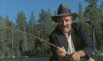 Movie still from “Johnny Got His Gun” (1971), directed by Dalton Trumbo – An older man holding a fishing pole in front of a body of water; Medium shot, Low angle