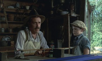 Movie still from “Johnny Got His Gun” (1971), directed by Dalton Trumbo – A man and a boy are working in a workshop; Medium shot, Over the shoulder angle