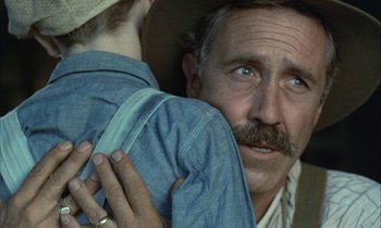 Movie still from “Johnny Got His Gun” (1971), directed by Dalton Trumbo – An older man holding a young boy in his arms; Close Up shot, Over the shoulder angle