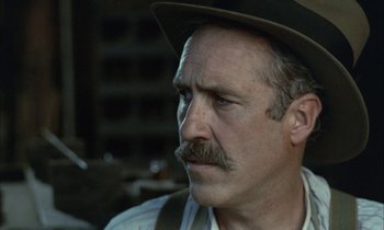 Movie still from “Johnny Got His Gun” (1971), directed by Dalton Trumbo – An older man with a mustache wearing a hat; Close Up shot, Over the shoulder angle
