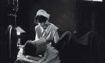 Movie still from “Johnny Got His Gun” (1971), directed by Dalton Trumbo – An old black and white photo of a nurse tending to a patient; Medium shot, Low angle