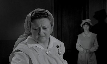 Movie still from “Johnny Got His Gun” (1971), directed by Dalton Trumbo – A woman in an old time nurse's uniform with her eyes closed; Medium shot, Low angle