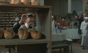Movie still from “Johnny Got His Gun” (1971), directed by Dalton Trumbo – An old man in a baker's shop with a bunch of loaves of bread on the counter; Medium shot, Over the shoulder angle