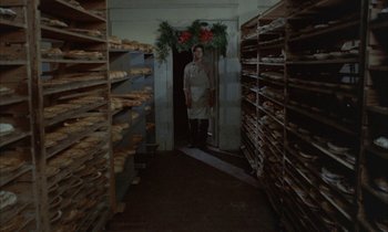 Movie still from “Johnny Got His Gun” (1971), directed by Dalton Trumbo – A man standing in the doorway of a room filled with stacks of wood; Wide shot, High angle