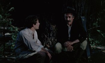 Movie still from “Johnny Got His Gun” (1971), directed by Dalton Trumbo – Two men sitting on the ground in the dark; Medium shot, Over the shoulder angle