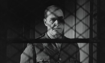 Movie still from “Johnny Got His Gun” (1971), directed by Dalton Trumbo – A man in uniform standing in front of a fence; Medium shot, Low angle