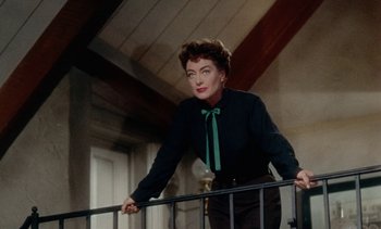 Movie still from “Johnny Guitar” (1954), directed by Nicholas Ray – An older woman wearing a black shirt and a green bow tie; Medium shot, Low angle